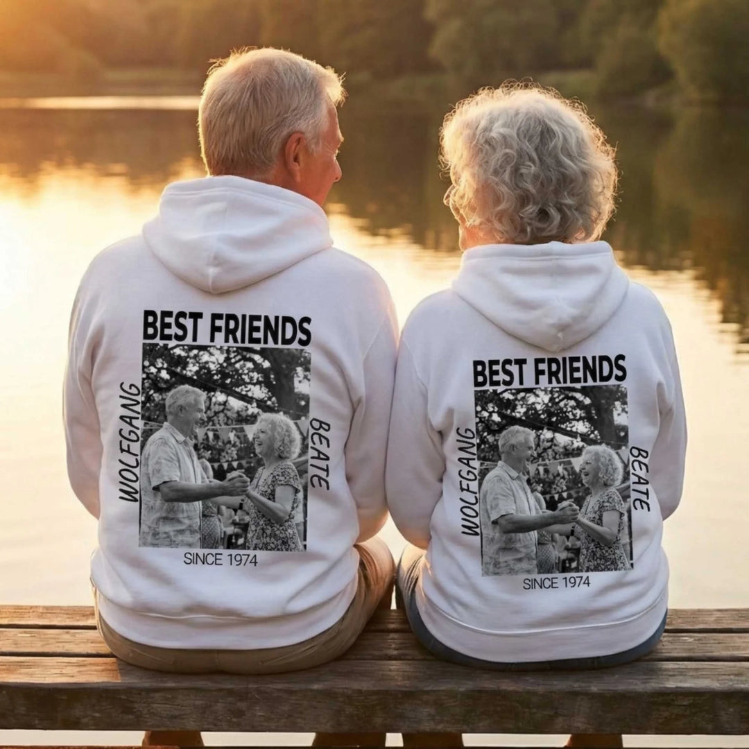 Ein Paar sitzt am Ufer und tragen einen personalisierten Hoodie mit dem Aufdruck Best Friends